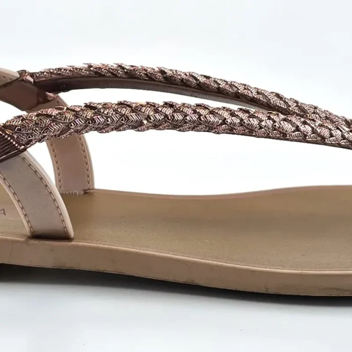Side view of Vintage Shoes Grendha sandals featuring braided rose gold straps and a beige sole