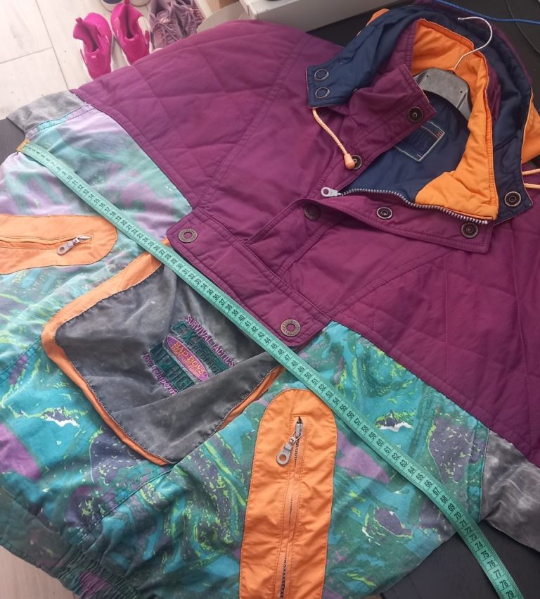 Person misst die Brustweite eines blauen Vintage Hoodies mit einem gelben Maßband - Vouge-Vintage Guide